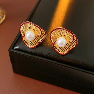 Macro shot of gold-plated heart earring with woven texture and a central white pearl