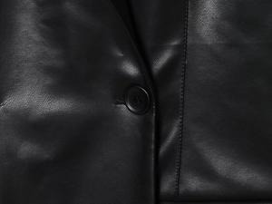 Close-up of the black leather blazer showing precise stitching and button details