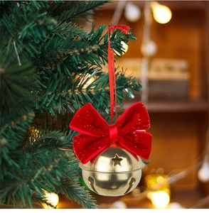 Close-up of a red velvet bow with a gold metal bell hanging on a Christmas tree branch