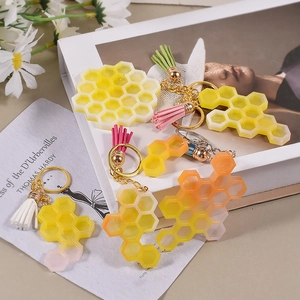 Détail des porte-clés alvéolés en résine avec pompons colorés sur un décor stylisé