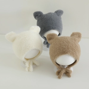 Detailed view of plush baby winter hats with bear ears in cream, grey, and brown