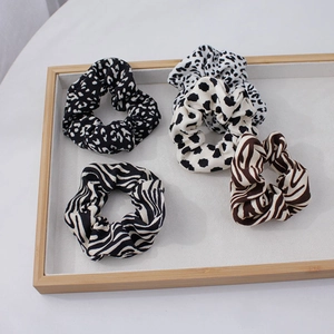 Détail de quatre chouchous en tissu aux motifs léopard et zèbre sur un plateau minimal
