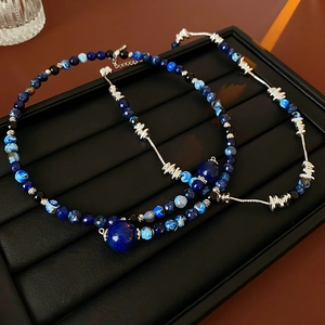 Detail of geometric beaded necklace featuring blue agate stones and silver spacers