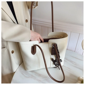 Close-up of a cream-white large capacity tote bag showing detailed texture and charms