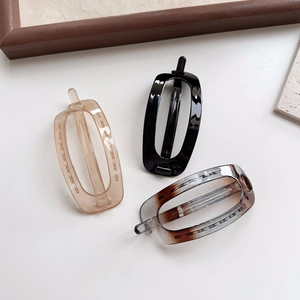 Close-up of three minimalist rectangular hair clips in amber, black and tortoiseshell resin