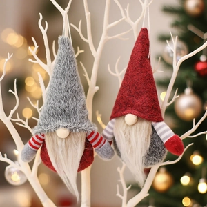 Christmas gnome plush ornaments in red and grey hanging on a white decorative branch