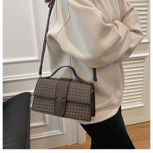 Detail view of the brown woven texture and metal hardware on a crossbody handbag