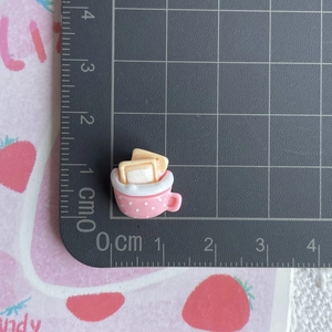 Macro shot showing 1.5cm miniature resin pink polka dot cup with toast on a scale