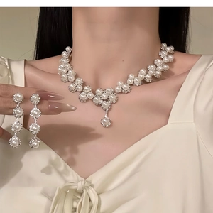 Detail of luxury pearl and rhinestone floral jewelry set worn by a model in soft lighting