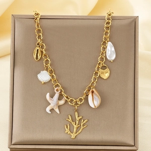 Close-up of 18K gold plated ocean charms with shells and starfish on a metal tray