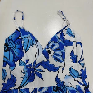 Dettaglio della stampa floreale blu e bianca sull'abito lungo con scollo a V e spalline