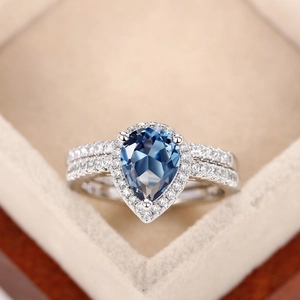 Makroaufnahme eines blauen Zirkonrings im Birnenschliff in einer beigen Samtbox