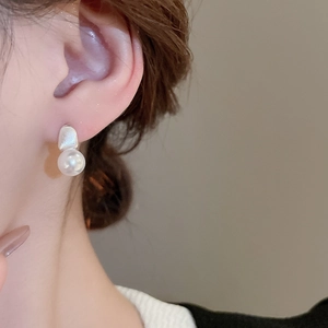 Elegant irregular silver metal stud earrings with dangling pearls worn by a model