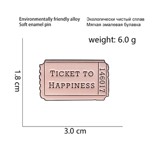 Detail of pink enamel brooch featuring Ticket to Happiness text and alloy texture