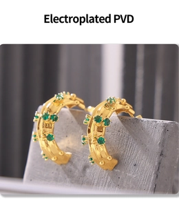 Detailed macro view of C-shaped 18k gold-plated earrings set with green gemstones
