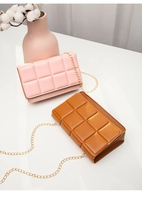 Pink and tan quilted chain crossbody bags with gold tassels on a white surface