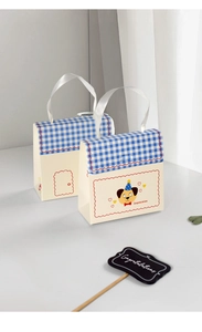 Detail of cute beige gift box with blue gingham lid, ribbon handle and Congratulations text
