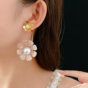 Close-up of elegant flower earrings with gold metal and pearly petals on a model