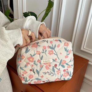 Detailed texture of quilted cotton makeup bag featuring floral patterns and brand label