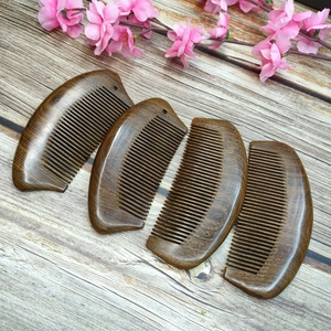 Detail of four curved black sandalwood hair combs arranged on a rustic wooden table
