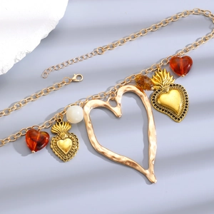 Macro shot of boho gold chain necklace with hollow heart and red resin charms