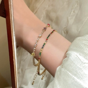 Detail of gold plated bracelets featuring colorful cubic zirconia and a rainbow tennis chain