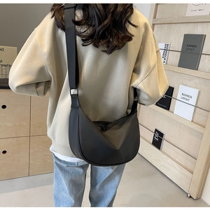 Detailed view of the black oversized moon bag worn by a model in a minimalist setting