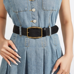 Vintage Y2K style black leather belt for women with ornate gold buckle on blue denim