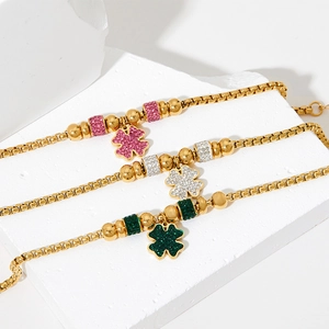 Three gold box chain bracelets with sparkling crystal four-leaf clovers in pink, white, and green