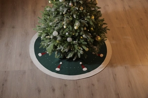 Détail du tapis de sapin de Noël tricoté vert avec motifs de bonnets de Noël et pompons