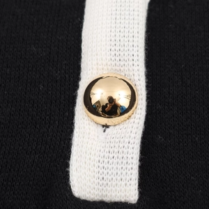 Makroaufnahme eines goldenen Kugelknopfs auf einem schwarz-weiß gestreiften Strickkleid