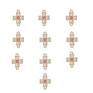 Close-up of golden cross charms with red evil eye centers and sparkling rhinestones