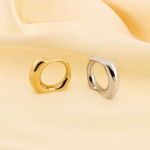 Detailed view of irregular 18k gold and silver plated rings on soft satin fabric