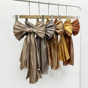 Detail of elegant satin scarves in earth tones with refined pleated texture and soft luster
