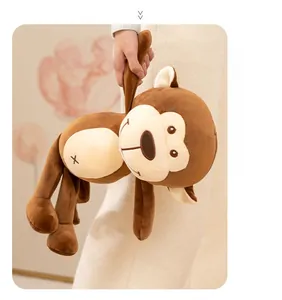 Detail of a brown stuffed monkey plush toy held by hands in a warm home setting
