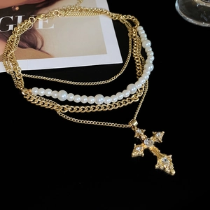 Detail of vintage layered necklace with pearl chain and crystal cross pendant on Vogue magazine