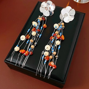 Macro detail of bohemian shell tassel earrings with silver flowers and colorful beads