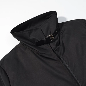 Détail du col d'un trench-coat noir avec boucle en cuir et finitions métalliques