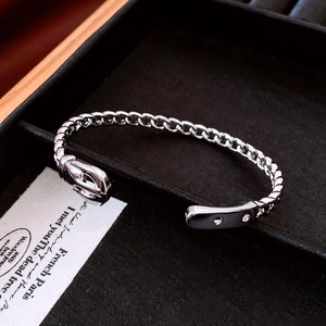 Close-up of silver chain buckle bangle on black velvet box with high-polish mirror finish