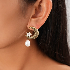 Close-up of vintage crescent moon earrings with rhinestones and white pearl detail