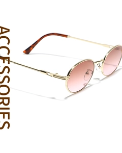 Detail of oval metal sunglasses with pink gradient lenses and gold engraved temples