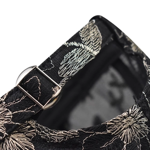 Detail of silver floral embroidery and adjustable silver metal buckle on a black lace cap
