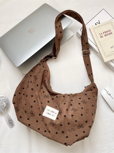 Brown corduroy crossbody bag with bow prints and adjustable strap in lifestyle scene