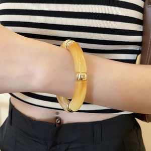 Close-up of amber acrylic geometric bracelet with gold-tone link connectors on wrist