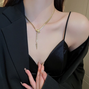 Close-up of golden snake-style Y-necklace with shiny scales worn on a model in a black suit