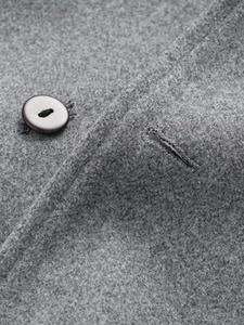 Detailed macro view of grey wool coat fabric texture and classic button closure detail