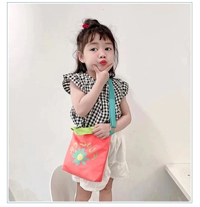 Detail of red canvas kids crossbody bag with flower print and green shoulder strap