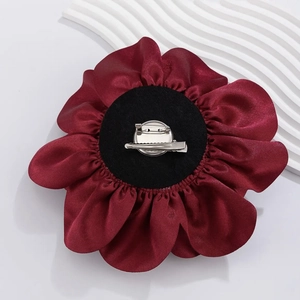 Detailed view of burgundy satin flower brooch with dual-use metal pin and duckbill clip
