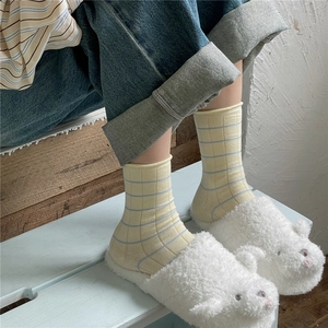 Close-up of Morandi yellow striped ribbed socks paired with white plush bear slippers