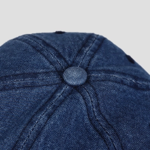 Detailed macro view of the dark blue denim baseball cap crown with stitched top button